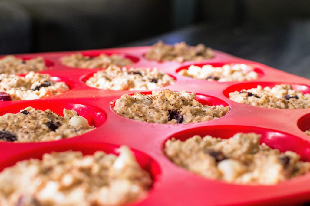 Oatmeal cranberry muffins in a red muffin tray.
