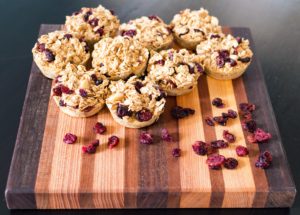 Oatmeal cranberry muffins on a wooden cutting board.