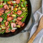 sausage and asparagus in cast iron skillet with wooden spoon