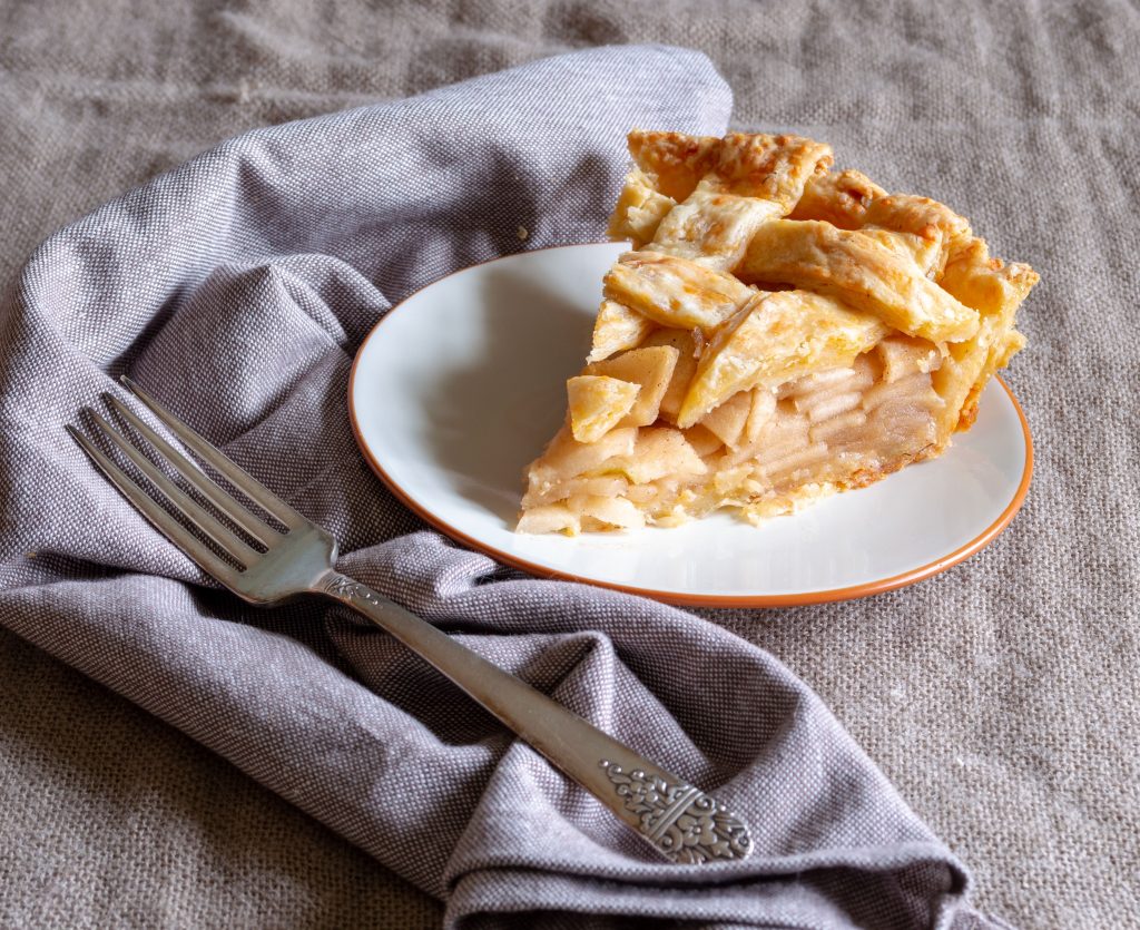 slice of cheddar apple pie sitting on white plate