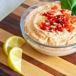 Roasted Red Pepper Hummus garnished with sesame seeds, parsley, and lemon.