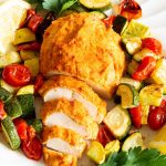 Hummus baked chicken on a bed of zucchini, squash and tomatoes.