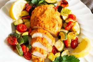 Hummus baked chicken on a bed of zucchini, squash and tomatoes.