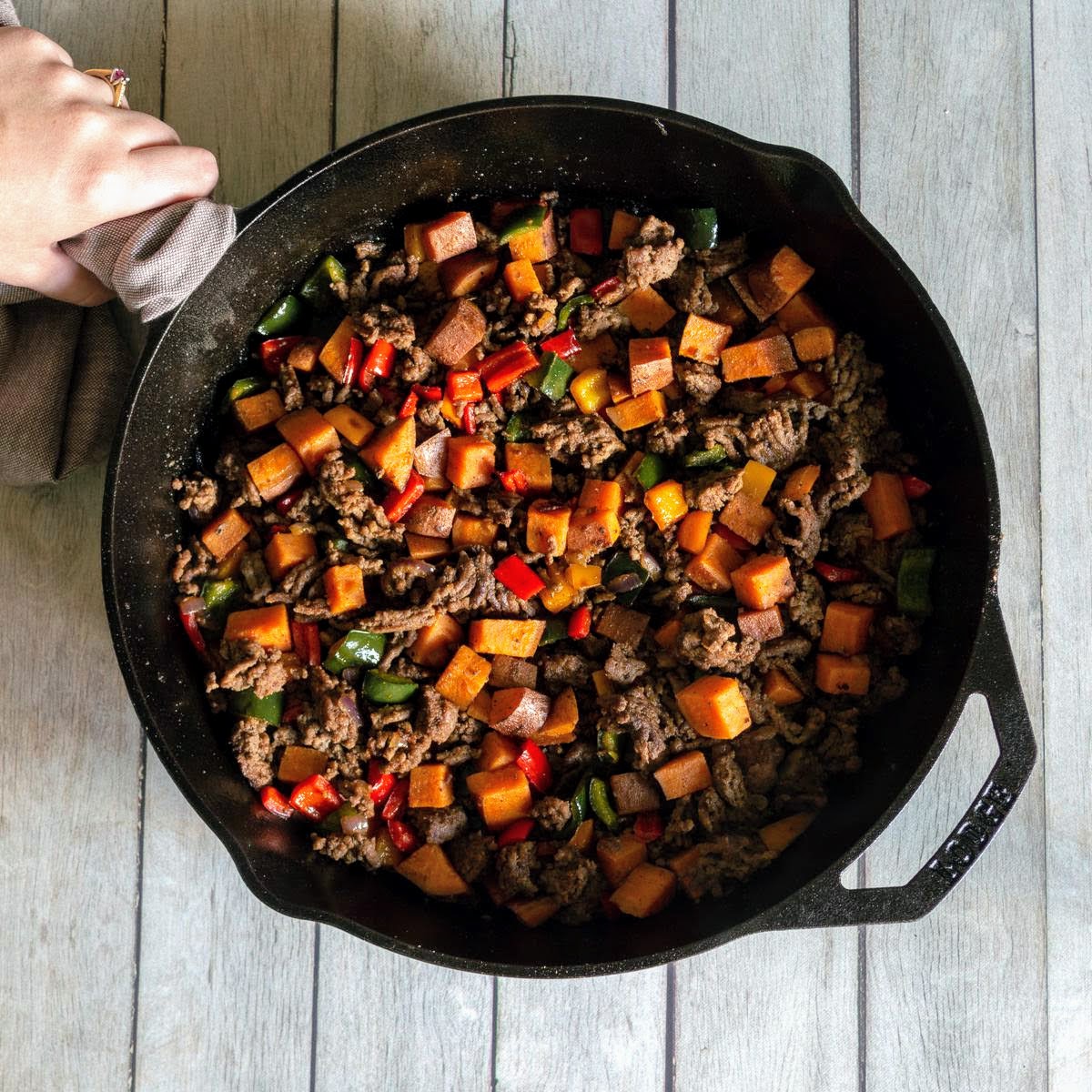Ground beef, sweet potatoes, peppers, in a cast iron skillet.