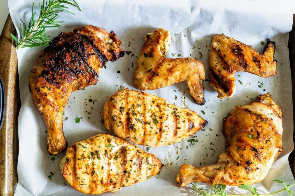 Mustard and herb grilled chicken on parchment paper with a sprig of rosemary and thyme.